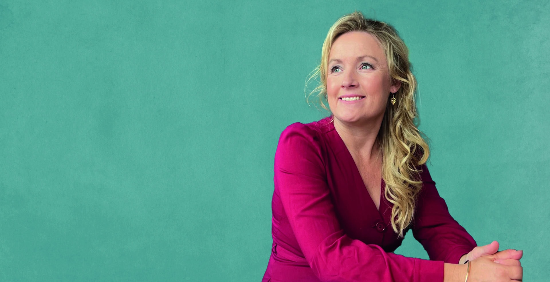 Pia Callesen i et professionelt portræt Pia Callesen smilende, professionelt portræt med grøn baggrund.