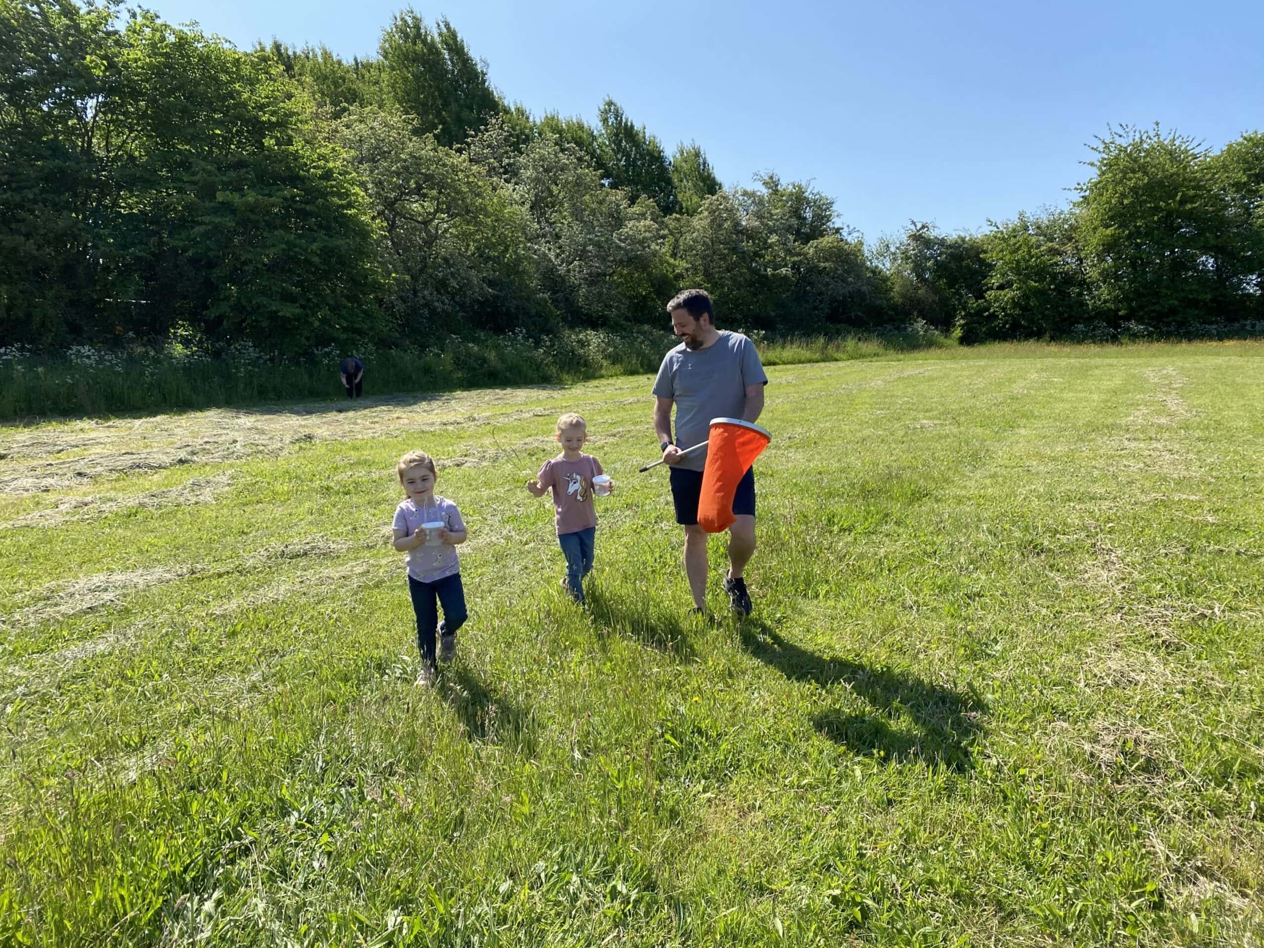 Familie med børn nyder Naturens dag i det grønne landskab.