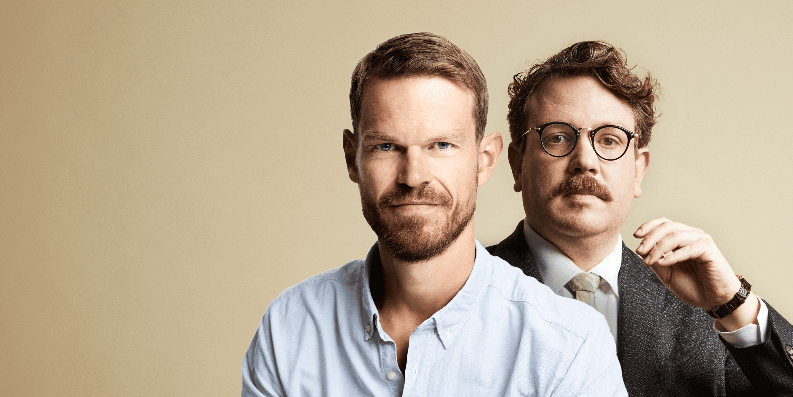 To mænd i professionel påklædning med neutral baggrund.