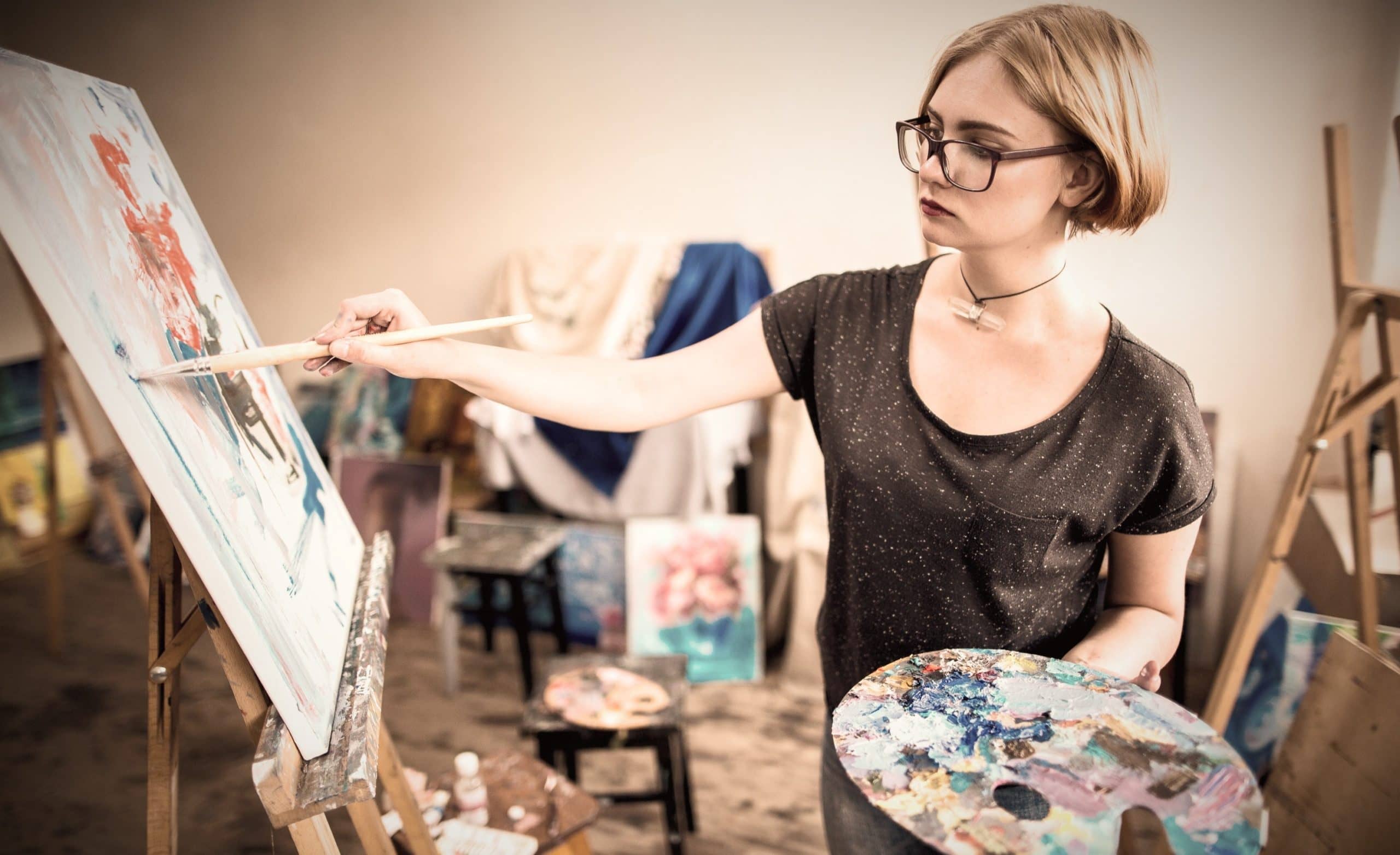 Kvinde maler på lærred under malerkursus på Sønderjyllands Kunstskole.