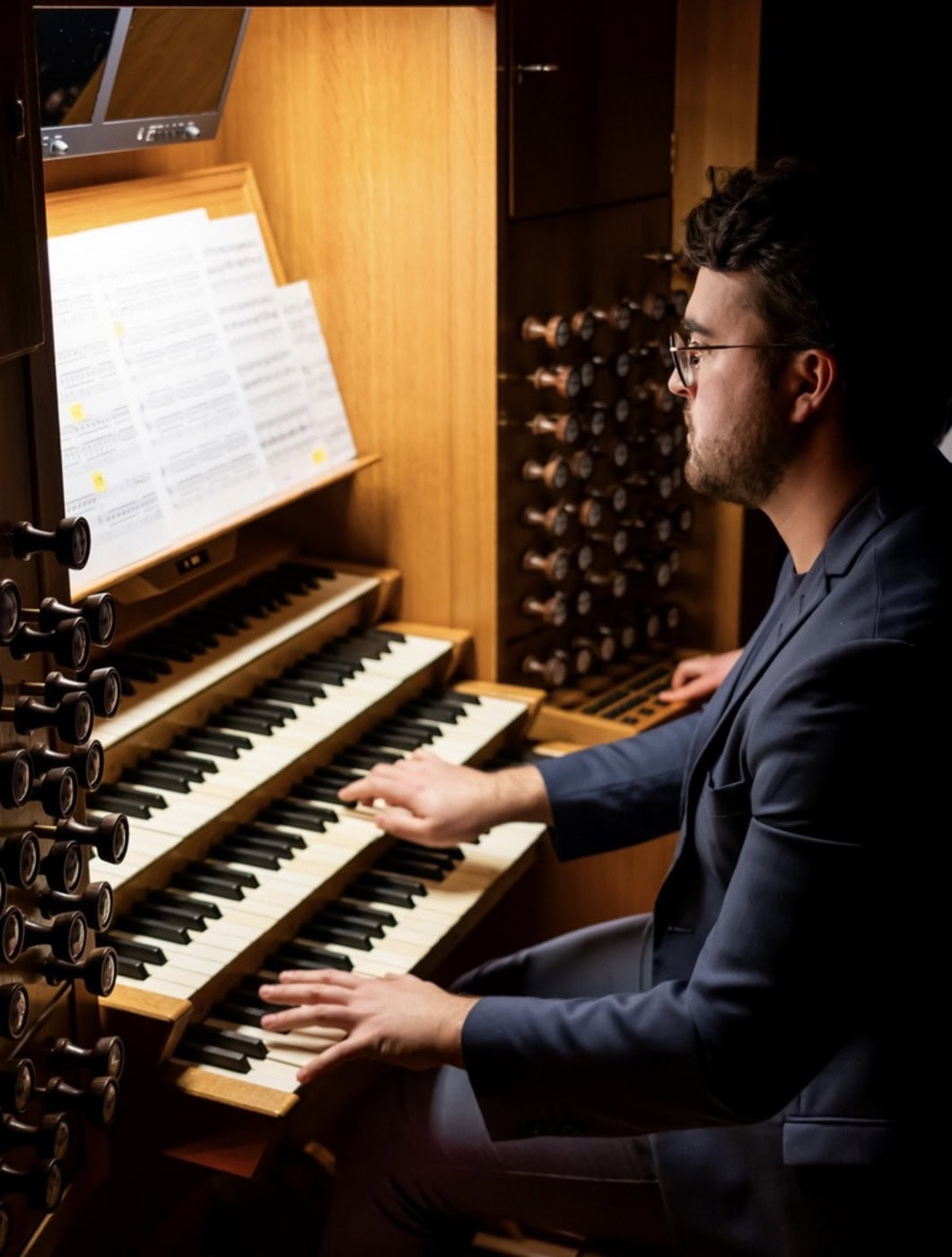Mand spiller orgel under koncert i kirke eller koncertsal.