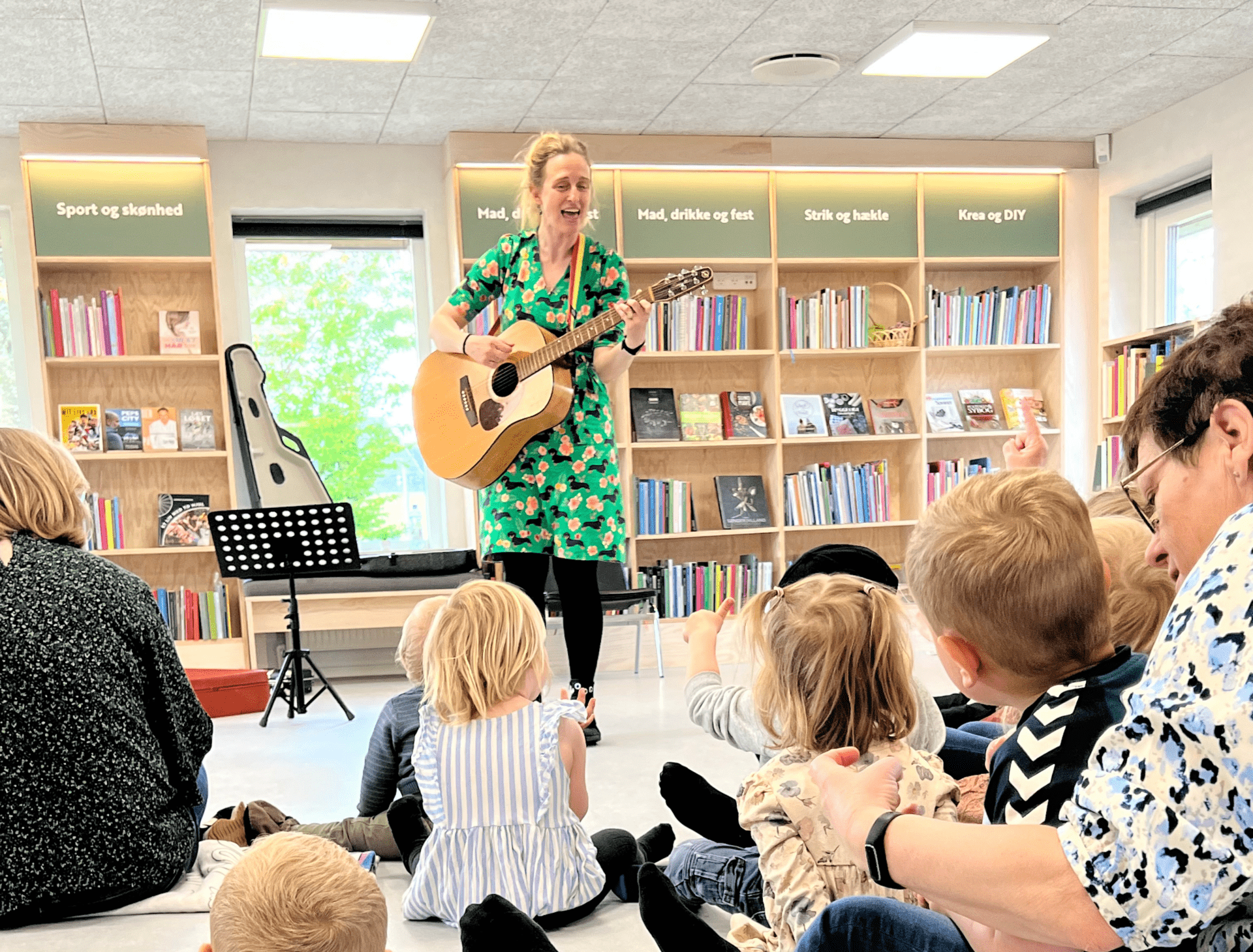 Karlas Tju-Hej i Sønderborg Kvinde spiller guitar for børn i biblioteket i Sønderborg.