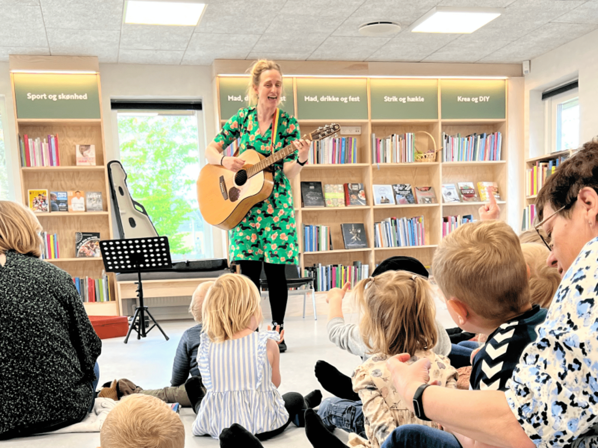 Karlas Tju-Hej i Augustenborg Kvinde spiller guitar for børn i biblioteket under Karlas Tju-Hej event.